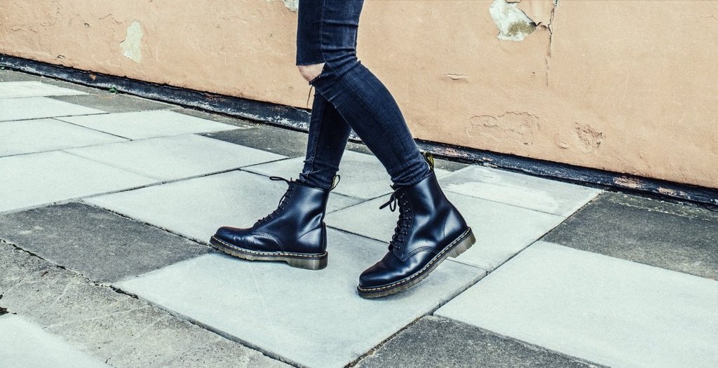 Seorang pria mengenakan sepasang ankle boots berwarna hitam, sedang berjalan di jalan setapak.